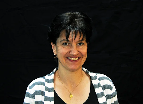 Michelle Julmi vom Verkaufsinnendienst, verantwortlich für die Kundenbestellabwicklung, posiert vor einem schwarzen Hintergrund.