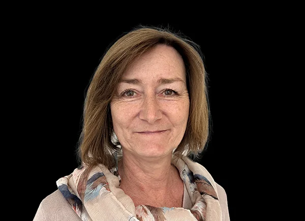 Romana Meier vom Verkaufsinnendienst, verantwortlich für die Kundenbestellabwicklung, posiert vor einem schwarzen Hintergrund.