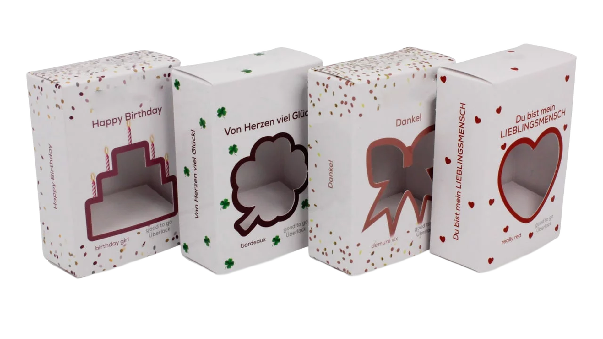Vier Faltschachteln mit ausgestanzten Fenstern in Form von Herz, Kleeblatt, Schleife und Torte mit Aufschriften wie „Happy Birthday“ und „Du bist mein Lieblingsmensch“.